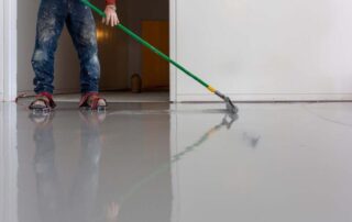 This image show a man applying epoxy on a floor.